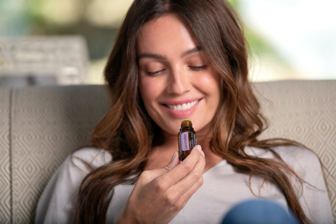 woman smelling essential oil from bottle