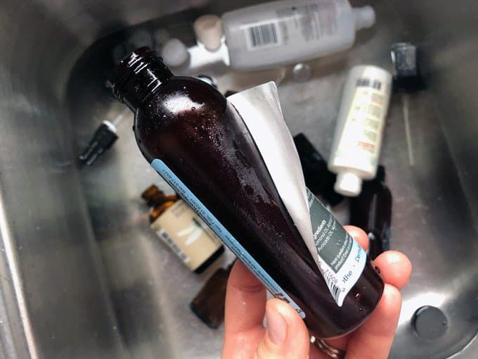 removing labels from recycled essential oil bottle