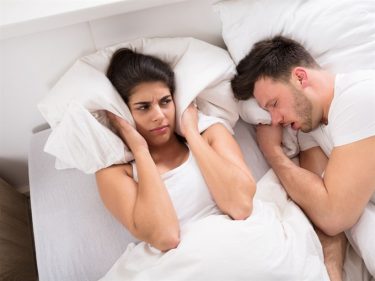 couple in bed, one partner is snoring