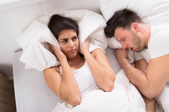 couple in bed, one partner is snoring