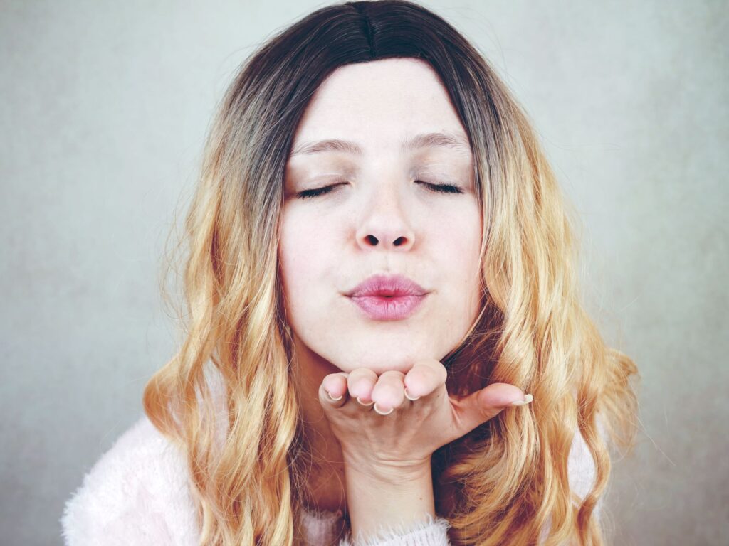 blonde woman blowing a kiss with closed eyes